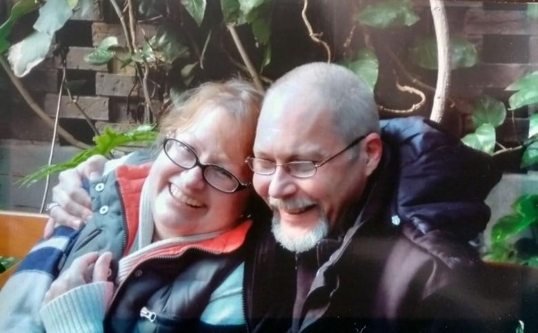 A man and woman smile in front of the Eiffel Tower.