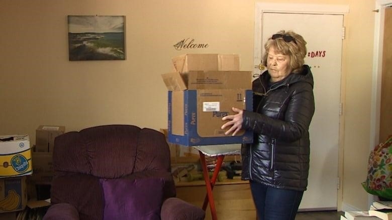 Woman moving boxes in an apartment.