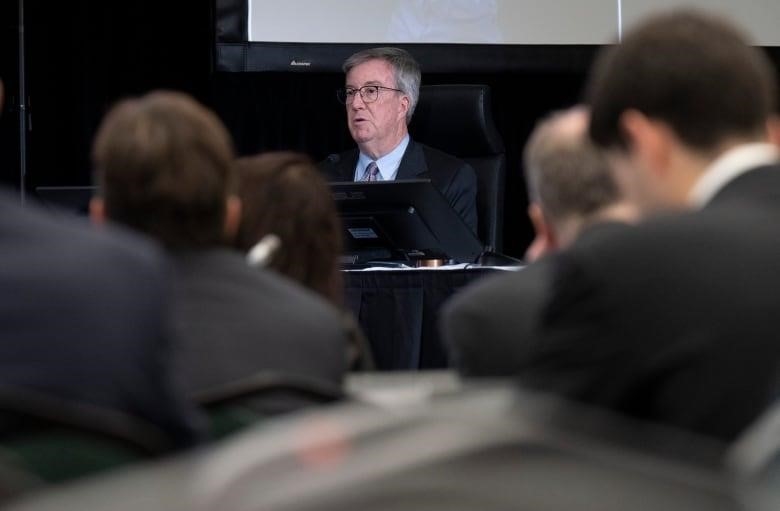 A politician at a desk, as seen from the middle of the audience.