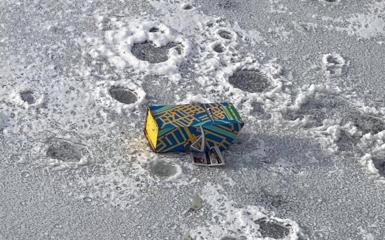 The Mainstreeter newspaper box lying face-down on the frozen surface of the canal.