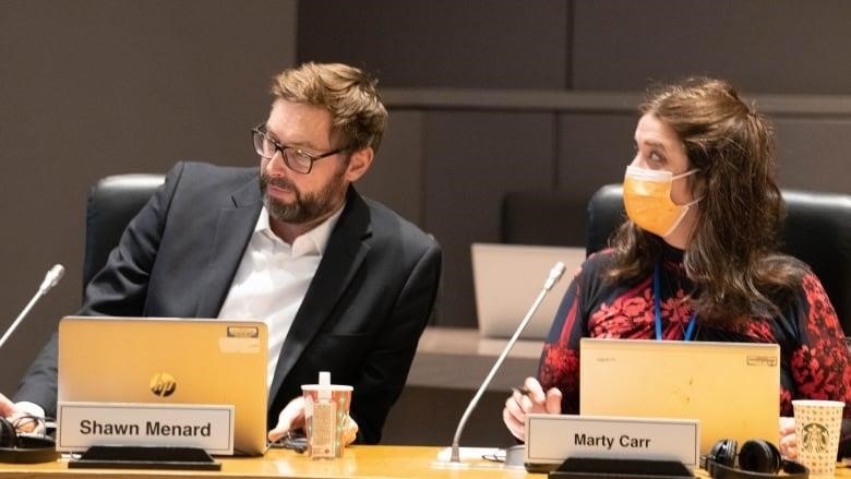 Two city councillors at a meeting table.