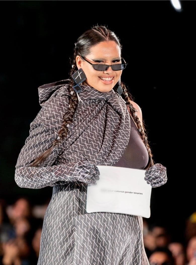 Model with long braided hair wearing a taupe coloured outfit.