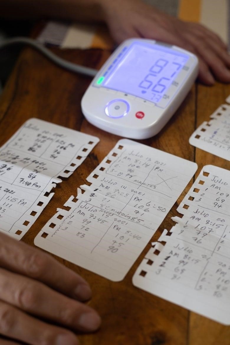 A machine that reads oxygen saturation levels reads 87 and 66. It rests on a table that also has other papers filled with handwritten notes.  