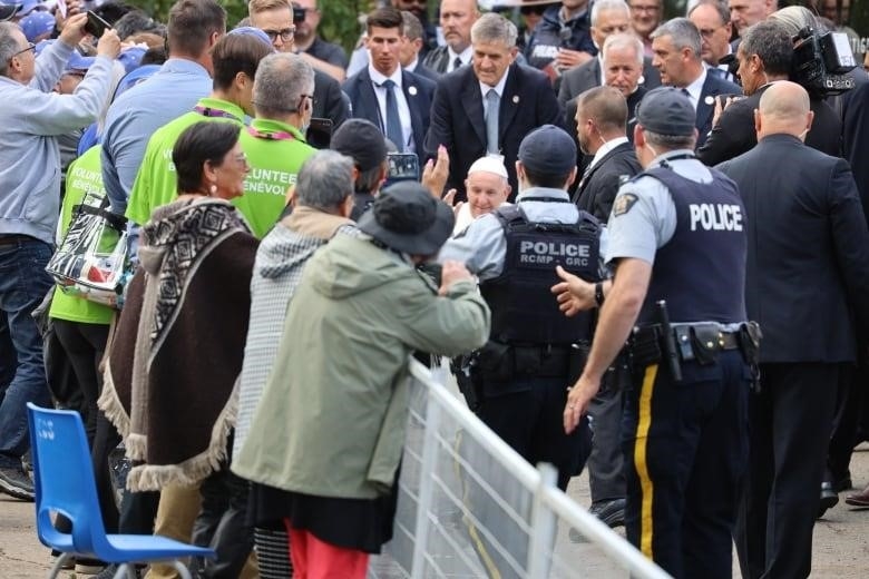 Pope Francis smiles as crowds, held back by police officers, wave to him outside Sacred Heart Catholic Church of the First Peoples in Edmonton.