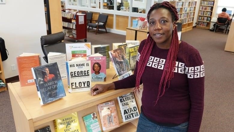 A woman stands next to a book display.