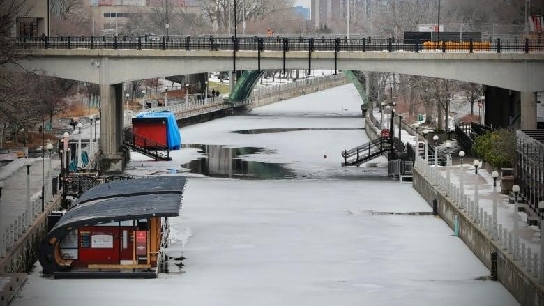 A partly frozen waterway with stairs and shacks on it.