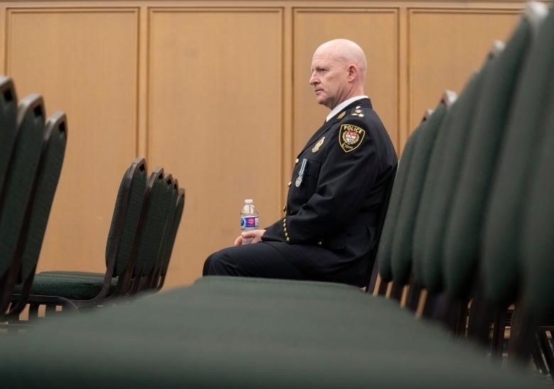 A police officer sits on a row of chairs.