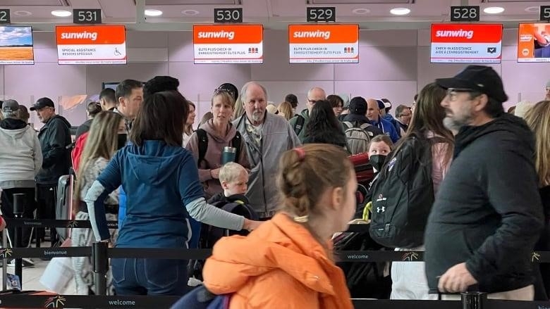 Travellers can be seen lining up at Sunwing airline representatives at Toronto Pearson Airport. 