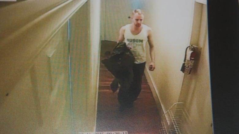A man is seen carrying a bag in a hallway.