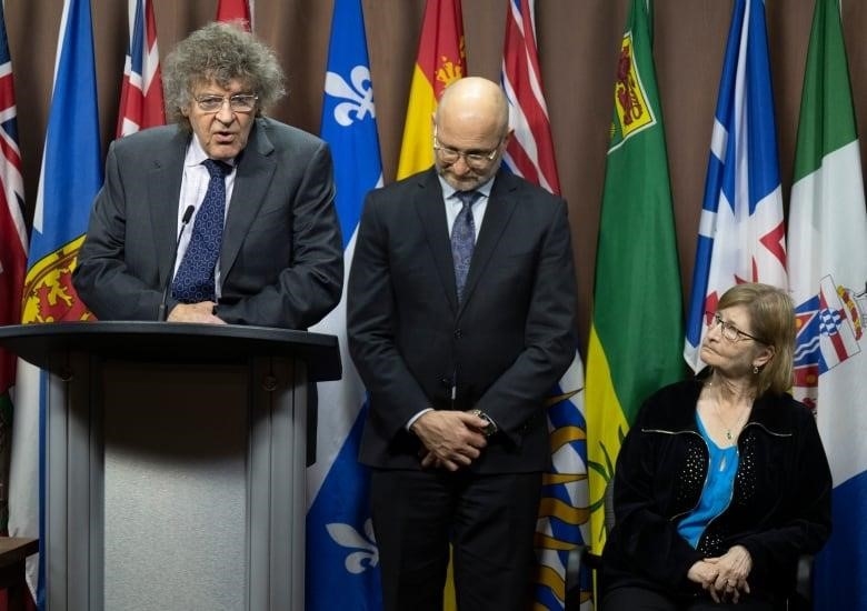 Minister of Justice and Attorney General of Canada David Lametti and Susan Milgaard, sister of wrongfully convicted David Milgaard, listen to lawyer James Lockyer speak during a news conference on Parliament Hill, Thursday.