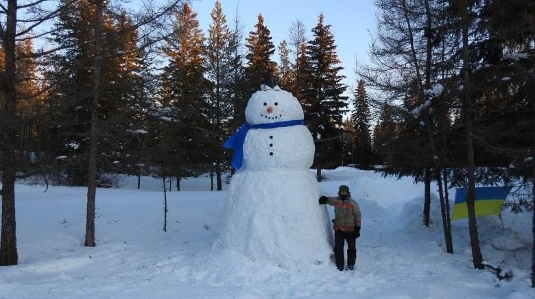 A man standing beside a snowman