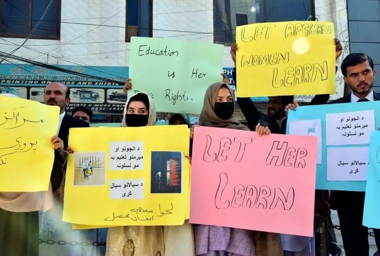Men and women hold up colourful signs bearing messages such as 'Let Afghan women learn' and 'Education is her basic right.'