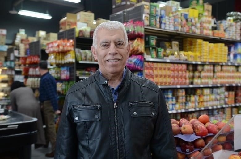man wearing leather jacket smiles in grocery store 