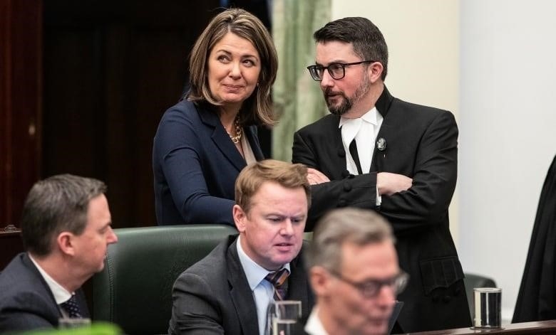 A woman smiles as she speaks to a man wearing glasses.