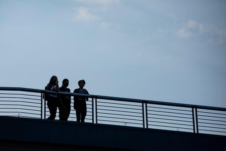Three students are silhouetted against a blue sky.