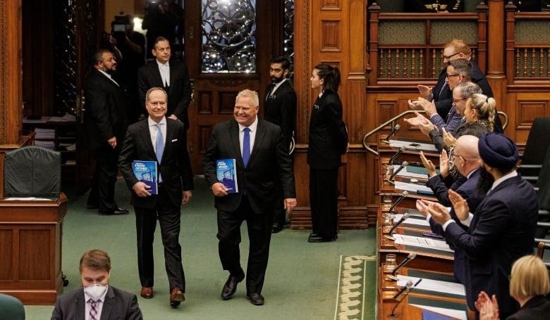 Premier Doug Ford and Finance Minister Peter Bethlenfalvy enter the chamber of the Ontario legislature with copies of the provincial budget on March 23, 2023.