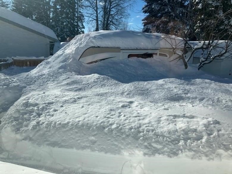 A camper is nearly completely covered by snowfall.