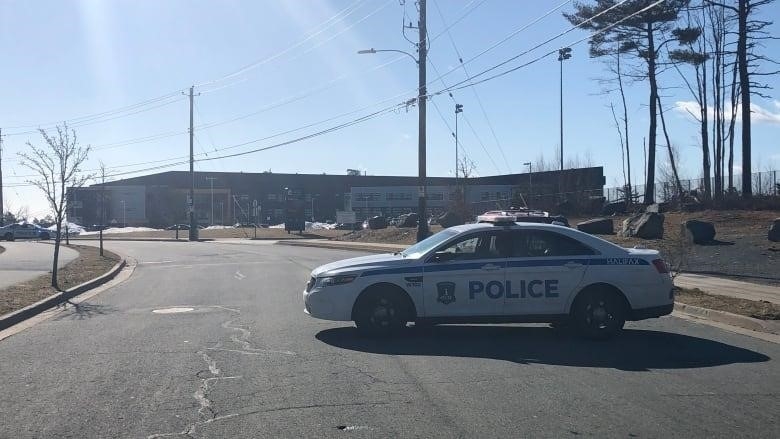 A police car is parked in front of a school. 