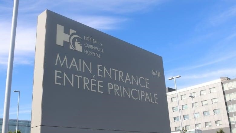 A grey sign points people toward the main entrance for a hospital.