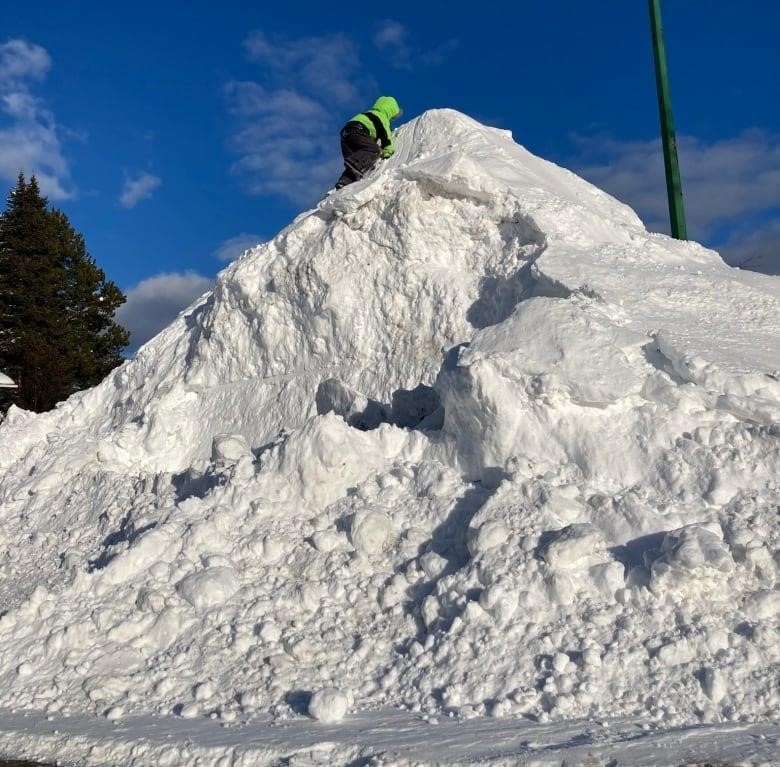 A child climbs a giant pile of snow.