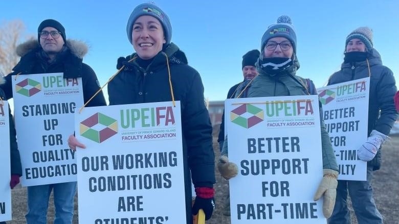 UPEI faculty members stand outside the main entrance to UPEI Monday, holding signs saying 'Better Support for Part-Time Faculty," and "Our Working Conditions are Students Learning Conditions."