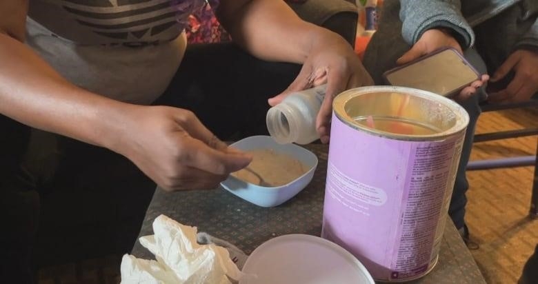 Gloria Luhaka prepares food for her youngest son on an ottomon in her motel room. 