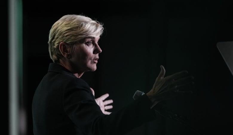 A woman gestures with her hands while giving a speech.