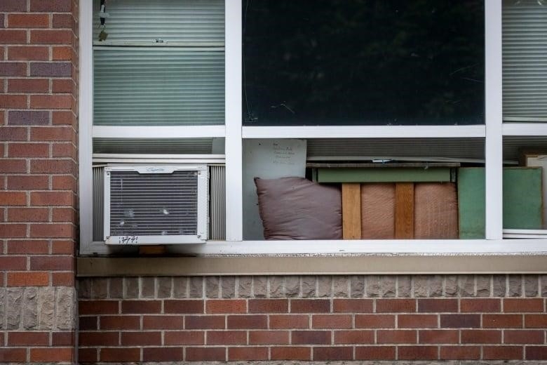 An air conditioner sits on the side of a window of an apartment.