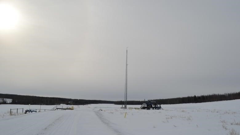 A gas well pad and tower stands in a snowy field in northeastern BC.