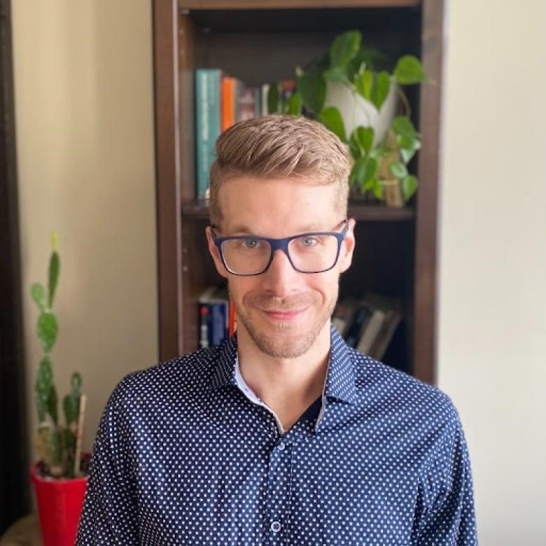 Portrait of young man with blond hair and glasses looking into camera