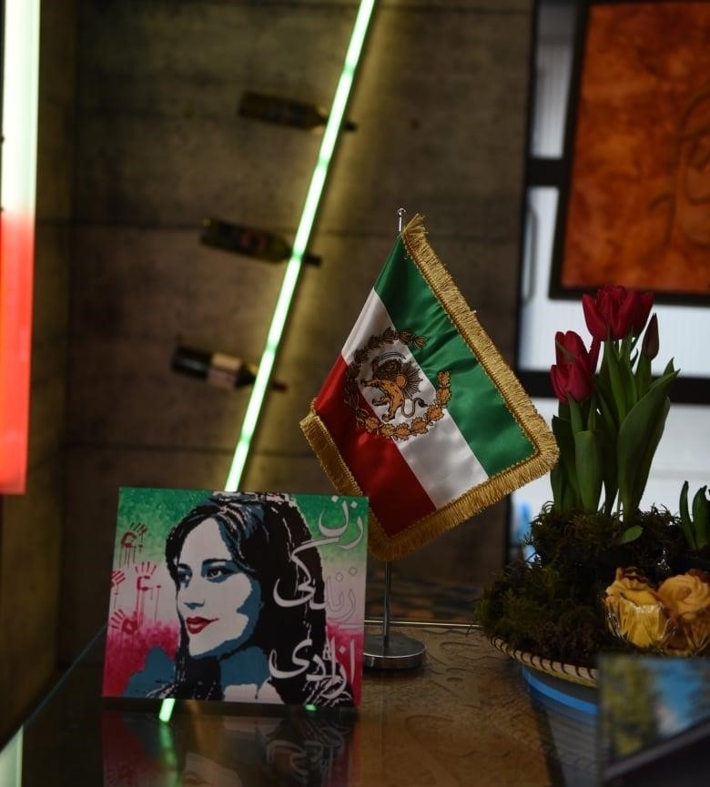 An Iranian flag and a painting of Mahsa Amini sit on a table at the Nowruz market. 