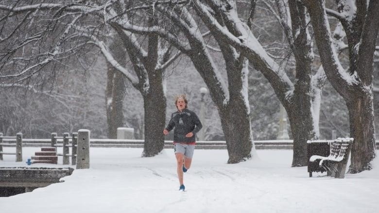 A jogger (in shorts!) runs on a snow-covered path.