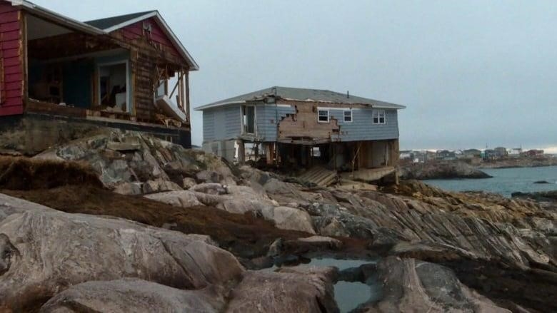 Homes located beside the ocean are heavily damaged by a storm.