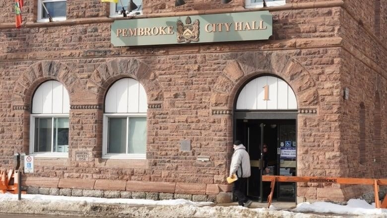 A person walks by a brown building.