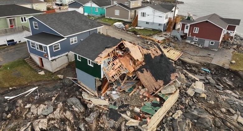 The side of a house is collapsed after a storm in a neighbourhood.