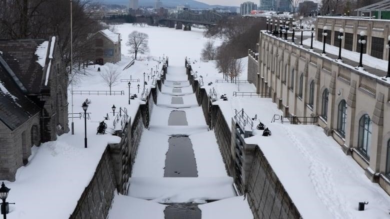 A snow-covered canal seen from above, surrounded by historic buildings.