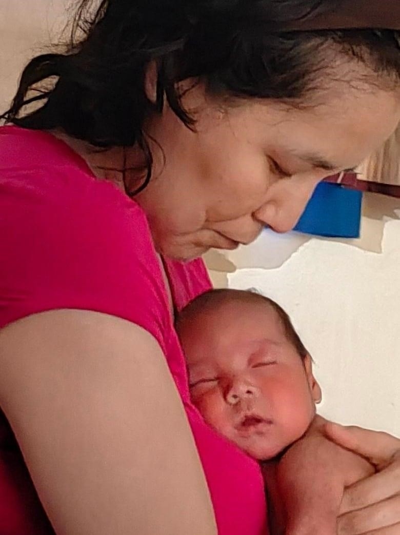 Mother in pink holding newborn.