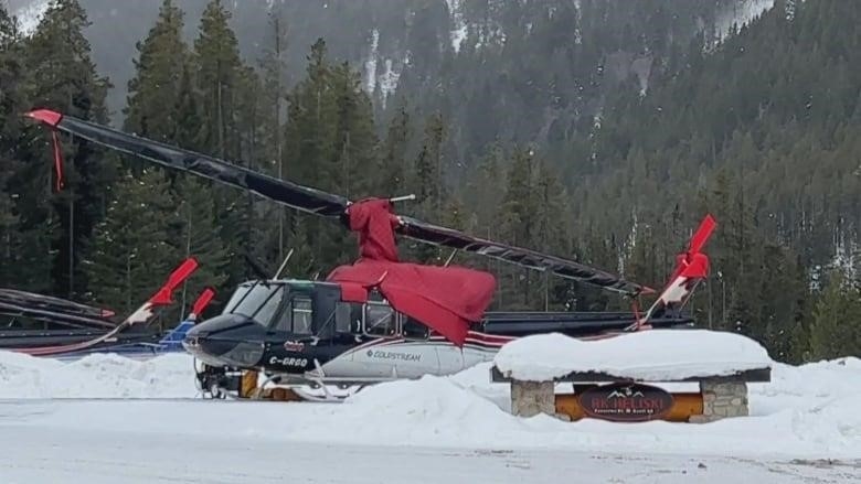 A black and red helicopter sits in the snow.