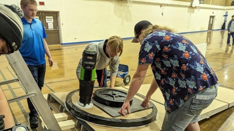 Students hold steady a hovercraft on a ramp which will accelerate it down a path