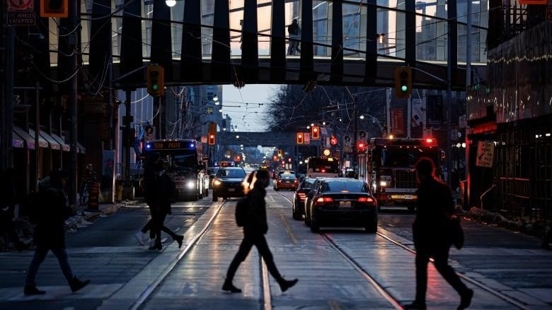 Pedestrians cross Queen St. during the evening commute on Feb. 15, 2022.