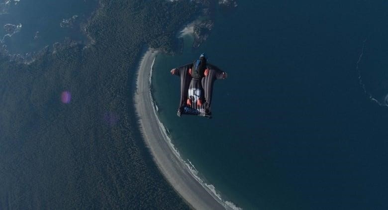 A shot of a person wingsuiting in the distance, from an aerial perspective.