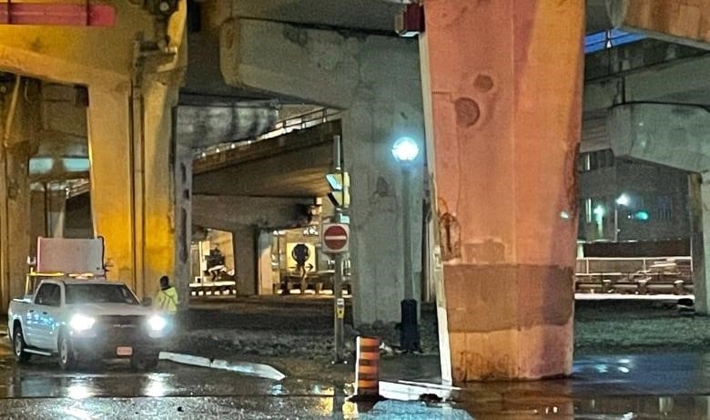 A photo of a vehicle stopped underneath the Gardiner Expressway. 