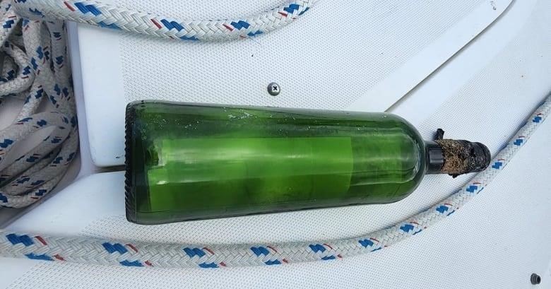 A wine bottle is shown by some rope on a boat.