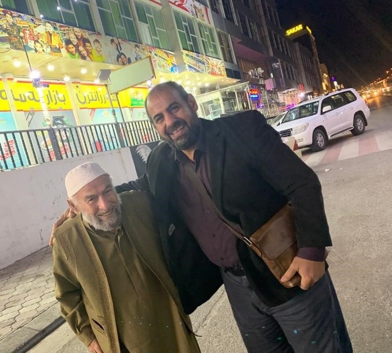 Two men hug on a street.