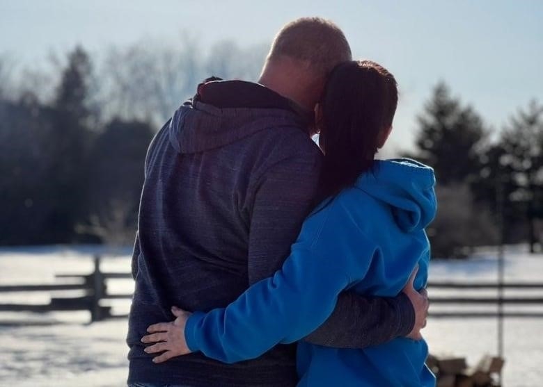 A man and woman hug.