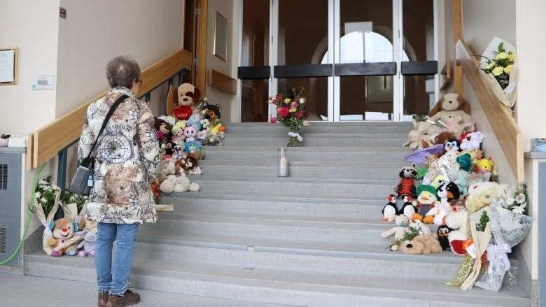 A woman stands in front of stairs full of flowers and stuffed animals 