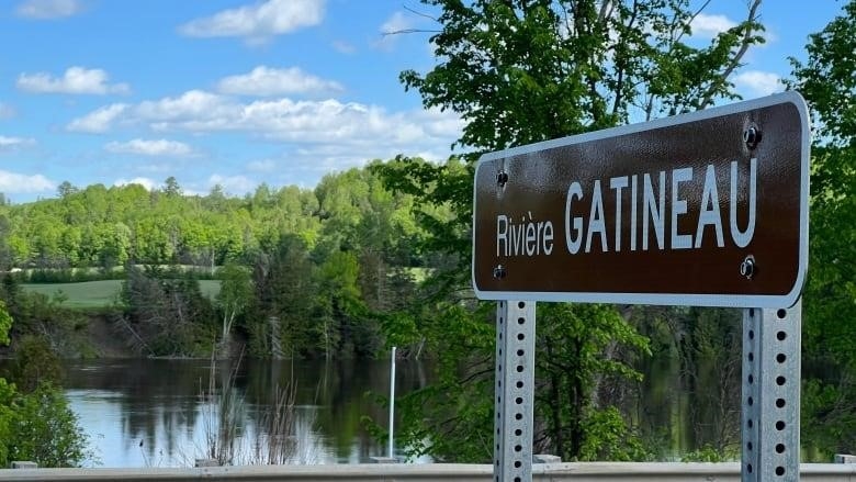 The Gatineau River flows past a sign along Quebec Route 105 near Farrellton, Que. on May 28, 2022.