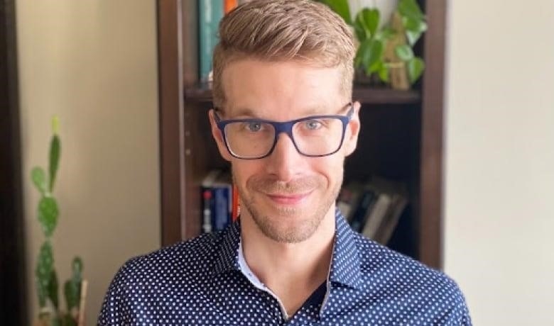 Portrait of young man with blond hair and glasses looking into camera