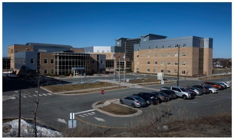 A four-storey building is shown, with cars in the parking lot in front of it.