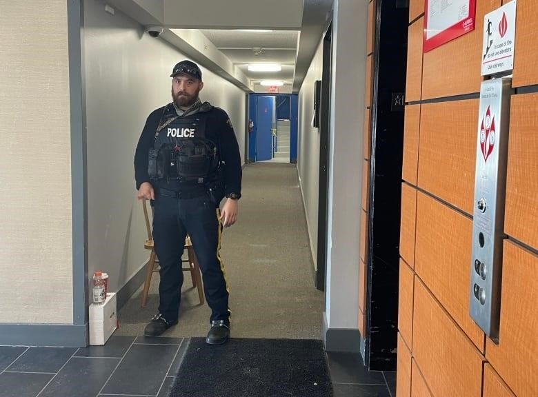 A police officer stands in an apartment hallway.